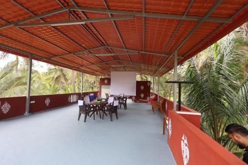 een restaurant met tafels en stoelen en palmbomen bij Coconut Sooru,Managed By Triora Escapes in Maddūr