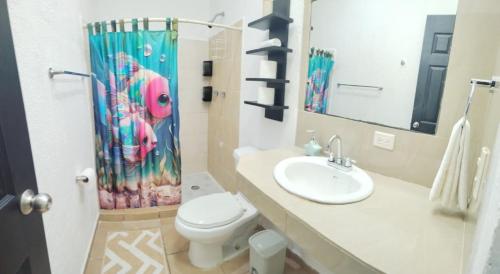 een badkamer met een wastafel, een toilet en een douchegordijn bij Casa Héroes in Cancun