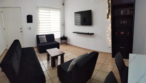 - un salon avec des chaises noires et une télévision dans l'établissement Casa Héroes, à Cancún