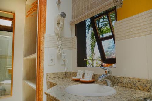 un bagno con lavandino e specchio di Pousada da Encosta a Garopaba