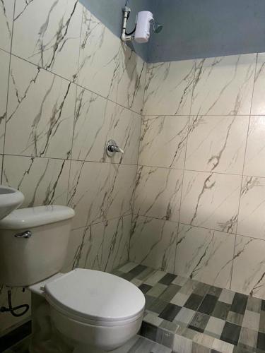 a bathroom with a white toilet and marble walls at Corcovado Pura Vida Stays in Puerto Jiménez