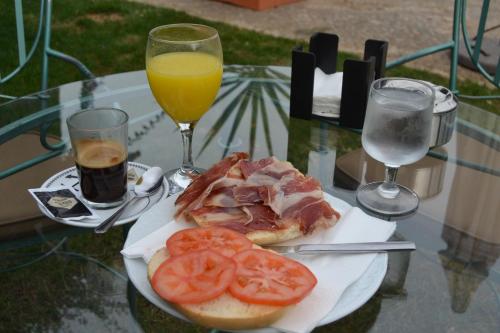Un plato con un sándwich y tomates sobre una mesa de cristal. en Lantana Garden, en Pilas