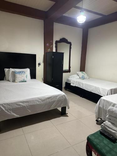 a hotel room with two beds and a mirror at LAS CAMELIAS APARTAHOTEL - La Virginia Risaralda in La Virginia
