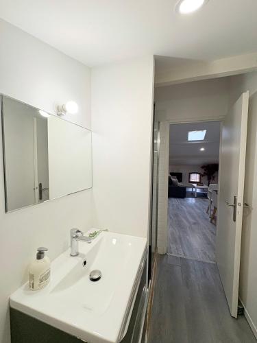 a white bathroom with a sink and a mirror at Le Refuge du Midi in Pamiers