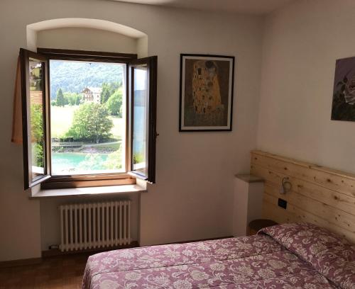 ein Schlafzimmer mit einem Bett und einem Fenster in der Unterkunft Trilocale sul Lago di Molveno in Molveno