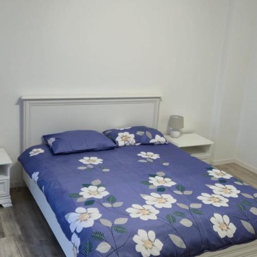 un letto con una coperta blu e fiori bianchi sopra di Central apartment Târgu Mureș a Târgu-Mureş