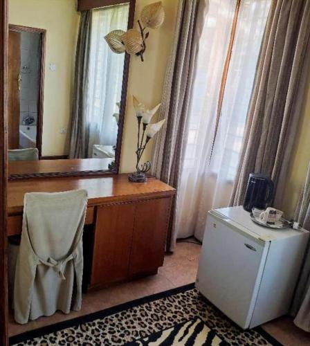 a bathroom with a vanity with a mirror and a refrigerator at Copperbelt Executive Accommodation Ndola, Zambia in Ndola