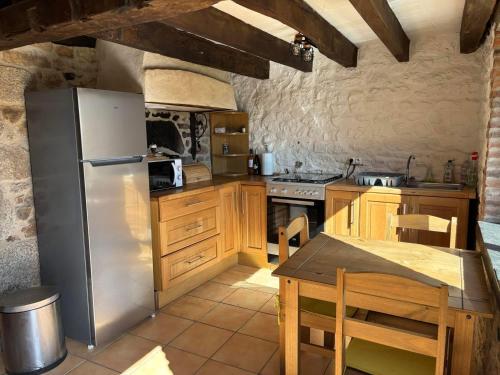 eine Küche mit Edelstahlkühlschrank und Holzschränken in der Unterkunft Maison typique Auvergne in Montel-de-Gelat