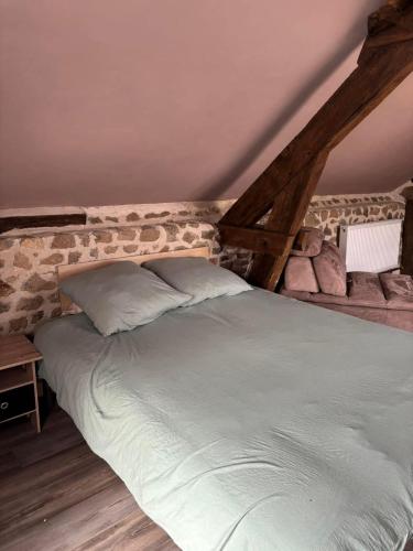 a large bed in a room with a stone wall at Maison typique Auvergne in Montel-de-Gelat