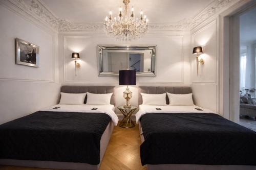 two beds in a room with a mirror and a chandelier at Sleephotels Alsterroom in Hamburg