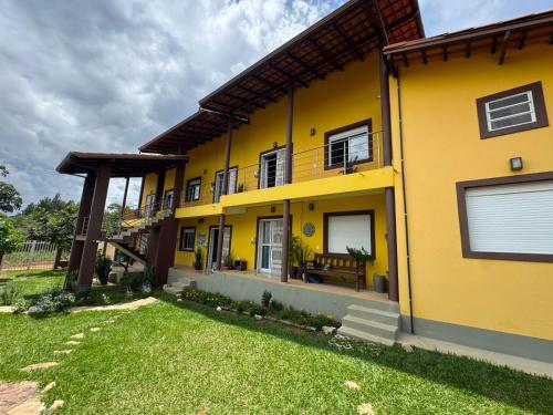 a yellow house with a lawn in front of it at Vila dos Cristais - Apartamentos de Temporada in Alto Paraíso de Goiás