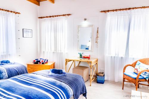a bedroom with two beds and a table and a desk at Meike's Guesthouse in Swakopmund