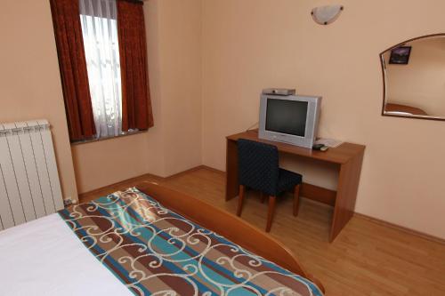 1 dormitorio con escritorio, TV y cama en Bed and Breakfast Malovec, en Divača