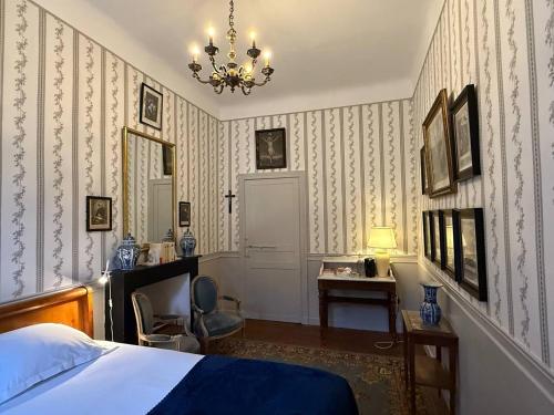 een slaapkamer met een bed, een bureau en een kroonluchter bij Chateau d'Estrac in Hastingues