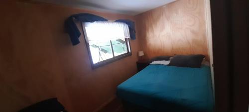 ein Schlafzimmer mit einem blauen Bett und einem Fenster in der Unterkunft Casa en la playa in Valdivia