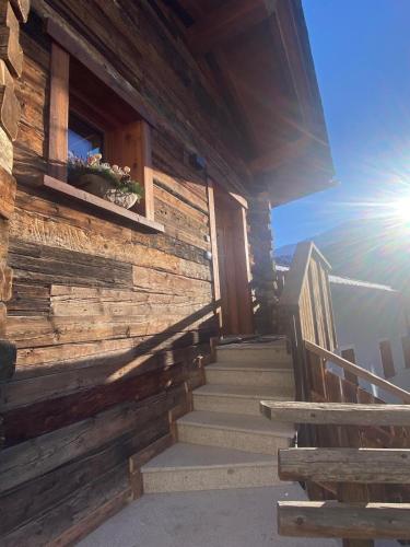 a wooden cabin with stairs leading up to a building at Il fienile in Valfurva
