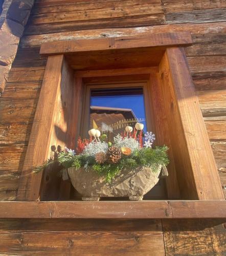 a window with a pot of flowers in a window box at Il fienile in Valfurva