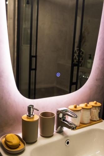 a bathroom sink with two cups and a mirror at Iria's Cozy House 2 in Sparta