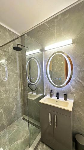 a bathroom with a sink and a mirror and a shower at Zarii Suites- Cotroceni in Bucharest