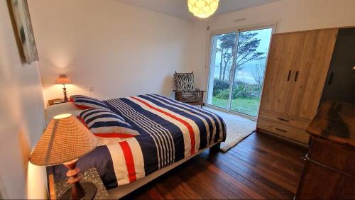 a bedroom with a bed and a large window at Magnifique T3 RDC vue mer-accès plage direct chez CATH in Trébeurden