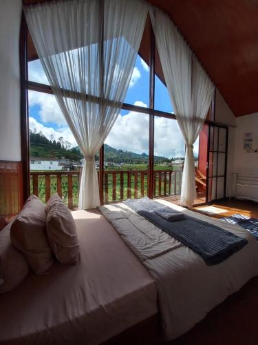 a bedroom with a bed with a large window at Cabin Wetan Kali Dieng in Diyeng