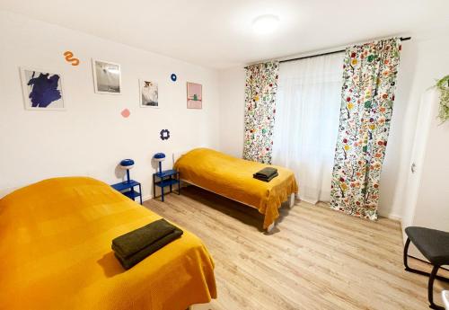 2 Betten in einem Zimmer mit gelber Bettwäsche in der Unterkunft Siegburg EG rechts in Siegburg