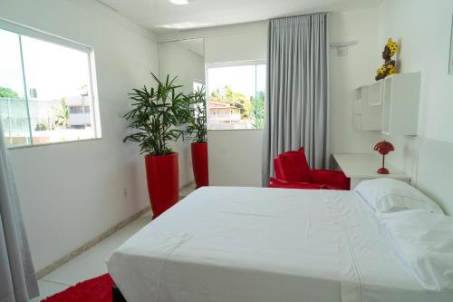 een slaapkamer met een wit bed en 2 ramen bij Casa de Temporada in Monte Gordo