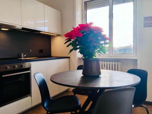 een keukentafel met een vaas met rode bloemen erop bij Charming Central Relais in Bergamo