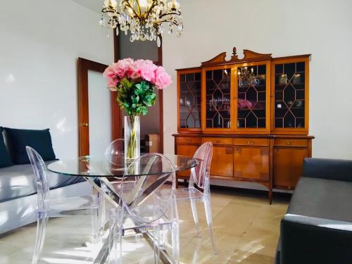 een eetkamer met een glazen tafel met roze bloemen bij Charming Central Relais in Bergamo