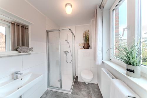 a white bathroom with a shower and a toilet at Der Ferienhof am Meer in Fehmarn