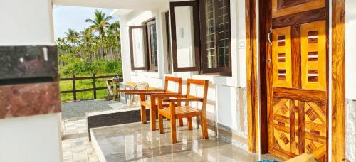 einen Tisch und Stühle auf der Veranda eines Hauses in der Unterkunft Jessie Villas in Sultan Bathery