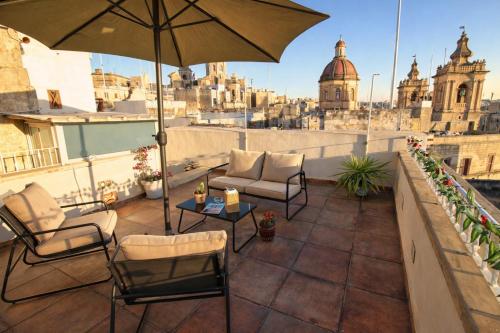 a patio with chairs and an umbrella on a roof at Birgu Square Townhouse, Rooftop & 3 Bathrooms in Birgu