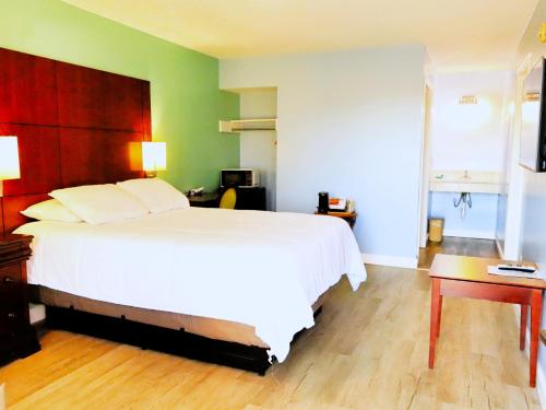 una camera da letto con un grande letto bianco e un tavolo di Americas Best Value Inn Suites & Studios Blytheville by Sonesta a Blytheville