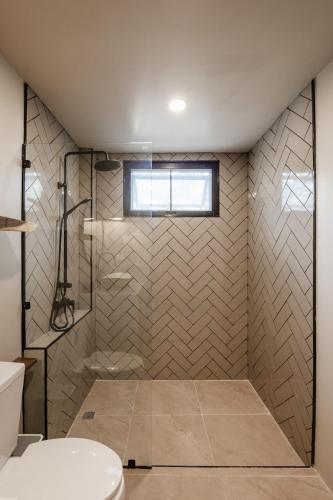 a bathroom with a shower with a toilet and a window at Aqua Luxe in Srithanu