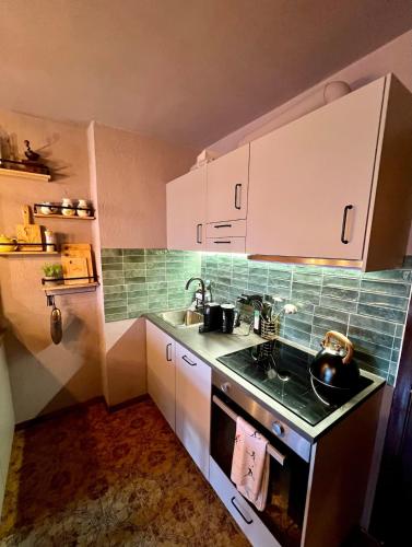 a small kitchen with white cabinets and a sink at The Mountain Escape - Luxury Apartment in Prato Nevoso