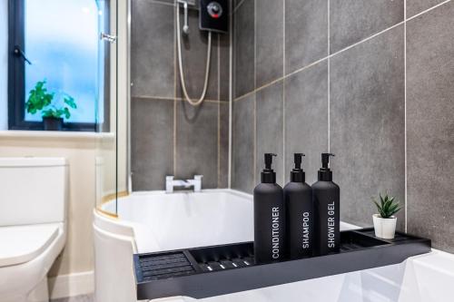 een badkamer met een badkuip met twee flessen op een aanrecht bij Bright 2BR Flat, Central Chatham, Parking in Chatham