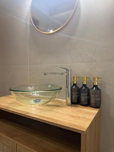 a bathroom with a glass sink and three bottles of soap at W Sam Las Komfortowy domek na skraju lasu z gorącą balia in Orzyny