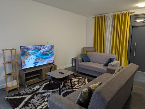 uma sala de estar com um sofá e uma TV de tela plana em 2 Bedroom House at Ayi Mensah Park em Aiyimensa