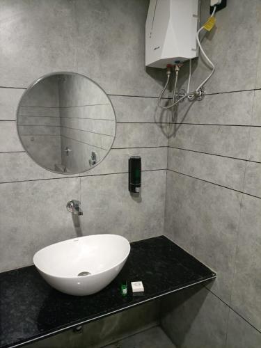 a bathroom with a white sink and a mirror at Hotel Divine in Junagadh