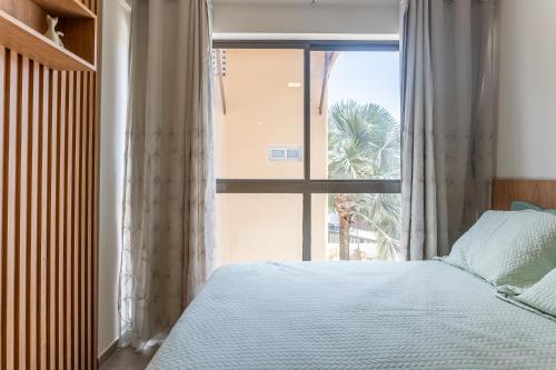 a bedroom with a bed and a large window at Season Smart Flat Ipojuca in Porto De Galinhas