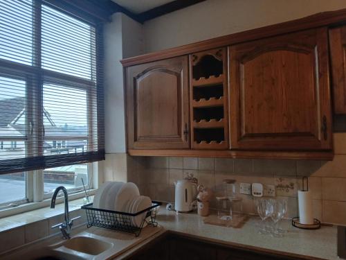 een keuken met houten kasten, een wastafel en een raam bij Central Bewdley - Load Street Retreat in Bewdley