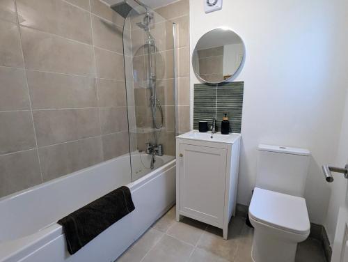a bathroom with a tub and a toilet and a mirror at 2 Bedroom House with Garden and Free Parking -10 min to London Bridge and near Lewisham Hospital in Lewisham