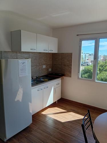 una cucina con mobili bianchi, un tavolo e una finestra di Brusa 1 a Las Grutas