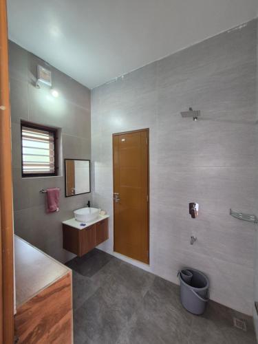 a bathroom with a sink and a toilet and a mirror at Prabhu Villla Upper Deck in Perumpāvūr