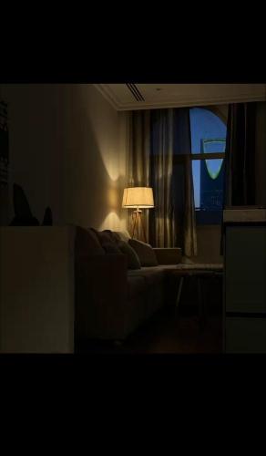 een woonkamer met een bank, een lamp en een raam bij #أستديو إطلالة الرياض in Riyad