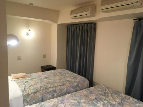um quarto de hotel com duas camas e uma janela em Hotel Crown Hills Oita em Oita