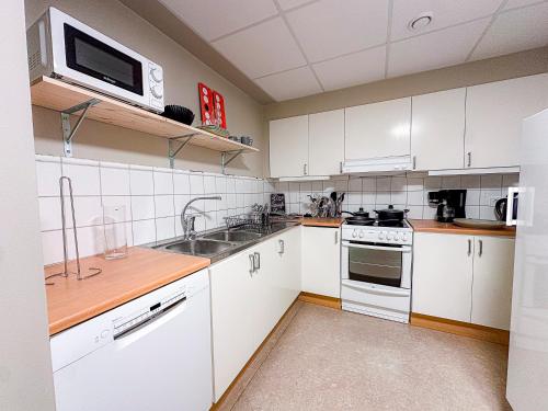 eine Küche mit weißen Schränken und einer Spüle und einer Mikrowelle in der Unterkunft Nässjö Vandrarhem in Nässjö
