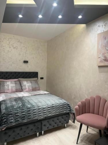 a bedroom with a bed and two pink chairs at ELLA LUX APARTMAN Čačak in Čačak