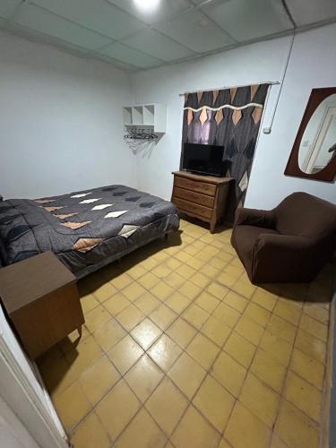 een slaapkamer met een bed, een stoel en een tv bij Casa in Miramar