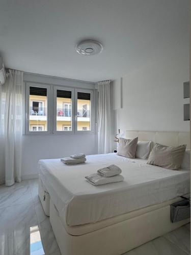 a white bedroom with a large bed with two towels on it at Apartamento IMPERIO 2 - Marbella centro in Marbella